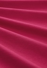 Tissu en coton fuchsia drapé avec une texture visible, présentant une surface lisse et mate et de douces plis créant de la profondeur et de la dimension.