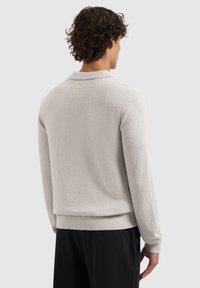 Hellgraues Pulloverhemd aus strukturiertem Stoff, mit Kragen, langen Ärmeln und geripptem Saum. Die Rückansicht zeigt minimale Details.