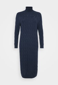 Langes, navy-blaues Strickkleid mit einem Rollkragen und strukturiertem Muster, vor einem schlichten weißen Hintergrund präsentiert.