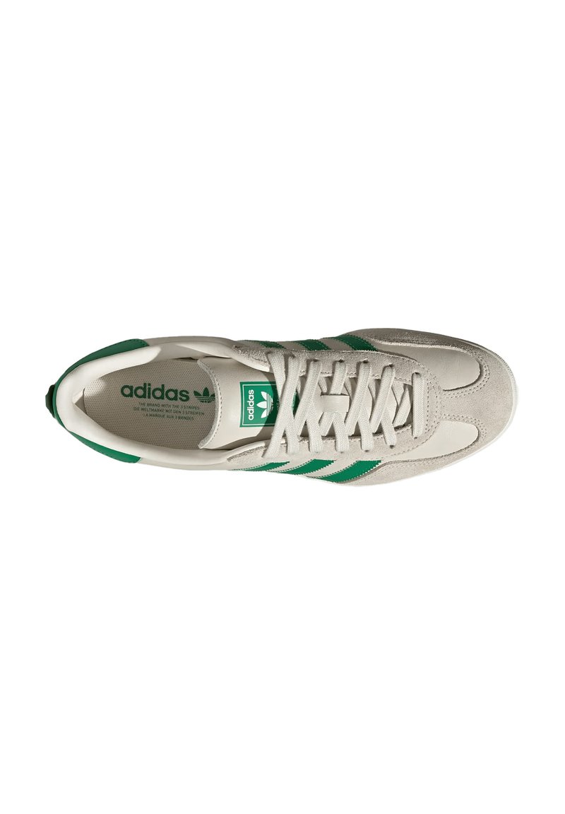 Basket gris avec des rayures et des lacets verts, arborant un logo Adidas sur la languette et une texture douce en daim. Vue de dessus.