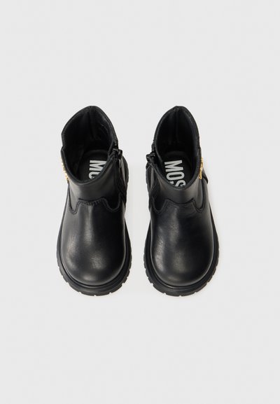 Botas de tobillo de cuero negro con un acabado suave, punteras redondeadas y suela de goma. Cuentan con cremalleras laterales y sutiles acentos de costura.
