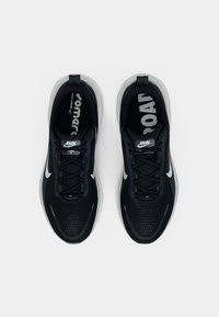 Pantofi sport negri cu partea superioară din plasă, prezintă accente albe, o talpă cu amortizare și șireturi texturate. Logo-ul este vizibil pe interiorul tălpii.