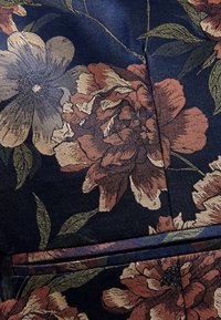 Blumenstoff mit einem marineblauen Hintergrund, der große Rosen- und Blumenmuster in Burgunderrot, Beige und Grün zeigt. Glatte Textur mit glänzender Oberfläche.