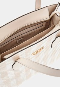 Gewebte weiße Handtasche mit beigen Lederelementen, die sich öffnen lässt und ein schlichtes beiges Innenleben sowie eine kleine Reißverschlusstasche offenbart. Goldene Hardware-Details.