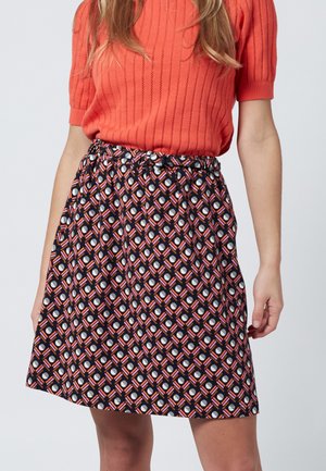 Patterned skirt with a black background featuring a geometric print in red, orange, white, and light blue. Elastic waistband with a subtle sheen.
