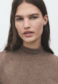Maglione marrone con collo alto e texture morbida. Il materiale sembra leggero e aderente, con una finitura liscia e dettagli minimi.