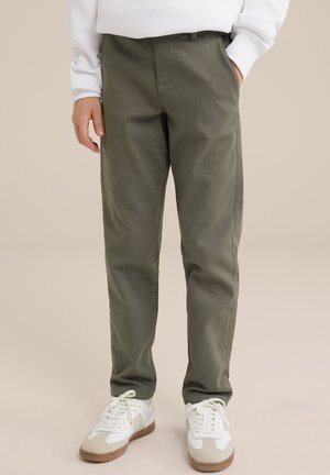 Pantaloni in cotone misto color verde oliva con design a gamba dritta, dotati di tasche frontali e una lieve texture. Abbinati a sneakers bianche e beige.