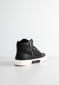 Black high-top sneaker featuring a combination of smooth and textured materials, a side zipper, and a white rubber sole.