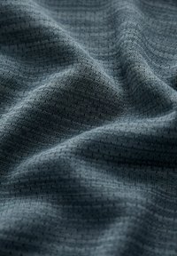 Tejido texturizado en azul oscuro con un sutil patrón de cuadrícula; material suave, tejido con ligero estiramiento e hilos negros entrelazados.