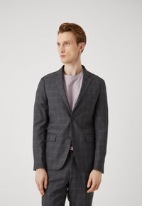 Grå rutet blazer med spisse krager og to knapper, kombinert med en lys rosa genser med rund hals. Glatt stoff og skreddersydd passform.