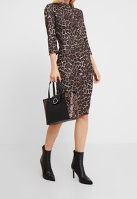 Kleid mit Leopardenmuster und Dreiviertelärmeln in figurbetonter Passform. Schwarze Handtasche mit strukturiertem Schlangenprint. Schwarze, gepolsterte Stiefeletten.