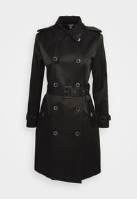 Svart trench coat med dubbelknäppning, stora knappar och bälte vid midjan. Har krage och sidofickor. Slät textur.