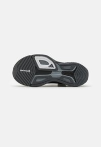 Suola di scarpa atletica nera e grigia con logo Continental, Torsion System e battistrada non marcante visibili su uno sfondo bianco.
