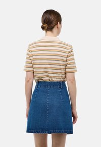 T-shirt à manches courtes rayé en beige et rouille, associé à une jupe en denim bleu taille haute, avec une coupe évasée classique et des poches.