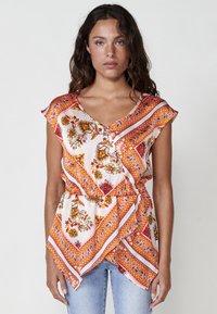 Top con patrón floral en blanco, con detalles en naranja y rojo. Escote en V con mangas cortas y diseño envolvente, hecho de tela ligera.