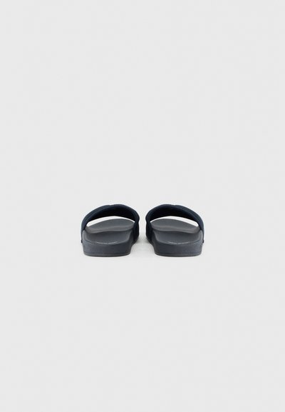 Tongs noires avec une semelle plate et des brides en caoutchouc texturé, présentant un design simple et une surface lisse.