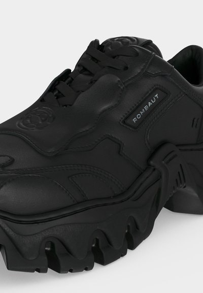 Μαύρο χοντρό αθλητικό παπούτσι με παχιά σόλα, υφασμένο επάνω μέρος, σχεδιασμό με κορδόνια και λογότυπο "ROMBAUT" στο πλάι.