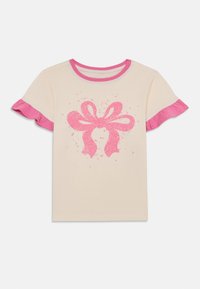 Kortermet kremfarget T-skjorte med rosa volangkanter, pyntet med en glitrende rosa sløyfegrafikk og spredte stjerneaksenter i midten.