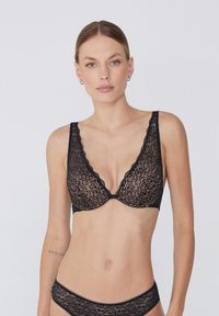Black lace bra with a plunging neckline, scalloped edges, and floral pattern. Soft texture, adjustable straps, underwire support.