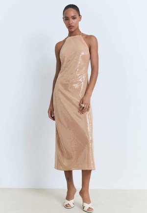 Nude flitrové midi šaty s halenkovým výstřihem, přiléhavým střihem, hladkým povrchem a elegantním drapováním, doplněné o bílé sandály na otevřenou špičku.