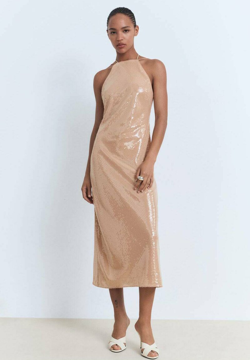 Vestido midi nude con lentejuelas, escote halter, forma ajustada, textura suave y un elegante caído, combinado con tacones abiertos blancos.