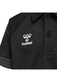 Svart polo skjorta med en texturerad yta, som har en placket med tre knappar och meshdetaljer på ärmarna. Inkluderar en vit logotyp på bröstet.