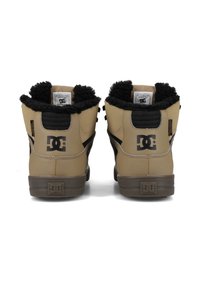 Rudi od tan spalvos odinių aukštakulnių sportbačių su juoda dirbtine anglų pakulne, paminkštintu apvadu ir DC logotipu. Ypatumai: kontrastingi juodi akcentai ir guminis padas.