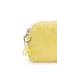 Keltainen tekstuuripussi, jossa on kohotettu lehtikuvio, vetoketjukiinnitys ja keltainen apinakalvo, joka on kiinnitetty hopeisella renkaalla.