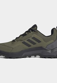 Olivově zelené sportovní boty s černými doplňky, texturovaným svrškem, šněrováním a odolnou gumovou podrážkou s výrazným vzorkem.