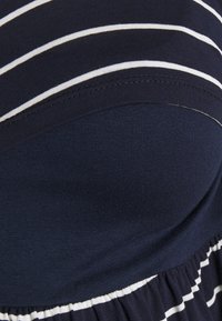 Granatowa sukienka z białymi poziomymi paskami, wykonana z miękkiej bawełny, z dopasowaną górą i rozkloszowaną, marszczoną spódnicą.