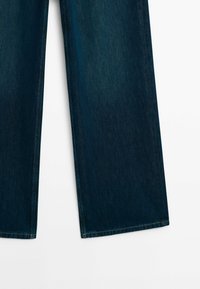 Jean en denim bleu foncé avec jambes droites larges, couture visible le long des coutures et des ourlets, posé à plat sur un fond blanc.