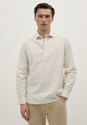 Light beige long-sleeve shirt with a half-button placket and a pointed collar, made from a textured fabric. Worn with light-colored trousers.