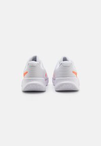 Weiße Sportschuhe mit einem strukturierten Mesh-Obermaterial, rosa Akzenten an der Ferse und einer Gummisohle mit einem gemusterten Griff.