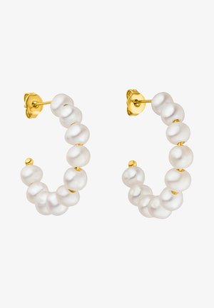 Boucles d'oreilles créoles en or avec des perles blanches inégales enfilées le long de la moitié avant de chaque créole sur un fond blanc.