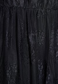 Tessuto in pizzo nero con un design testurizzato e motivi floreali, dalla superficie trasparente. Il materiale è leggero e scorrevole.