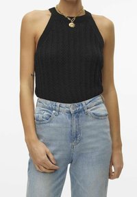 Czarny dzianinowy top bez rękawów z prążkowanym dekoltem, w zestawie z wysoko osadzonymi jasnoniebieskimi dżinsami o luźnym kroju i subtelnych przetarciach.