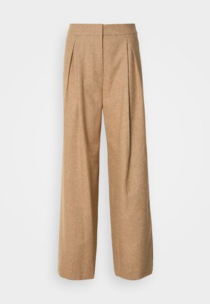 Pantalons larges en tissu texturé de couleur marron clair. Présentent des plis sur le devant et une taille haute, avec une finition lisse et sans fermetures visibles.