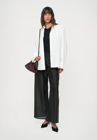 White button-up shirt, black top, black wide-leg pants, burgundy woven handbag, black pointed heels, smooth textures and relaxed fit.