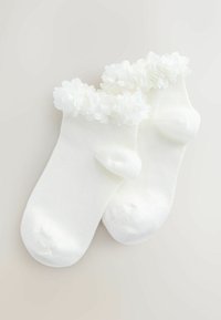 Fehér bokazokni bordázott textúrával, a mandzsettán puha, fehér anyagból készült virágdíszítéssel.