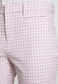 Pantalons en vichy lilas clair en tissu texturé, avec une taille plate, des poches latérales et une coupe ajustée.