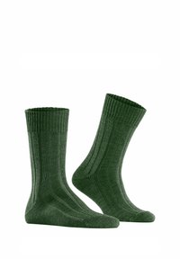 Ein Paar dunkelgrüne, gerippte Crew-Socken, die auf unsichtbaren Fußformen präsentiert werden, und dabei Dehnbarkeit und Struktur vor einem weißen Hintergrund zeigen.