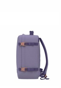 Zaino viola con una texture di tessuto liscia. Presenta spallacci regolabili e una chiusura con fibbia frontale. Forma rettangolare con una maniglia superiore.