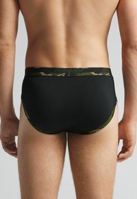 Bóxers negros con una cinturilla de patrón de camuflaje. Tela suave, diseño ajustado y cortes bajos en las piernas.