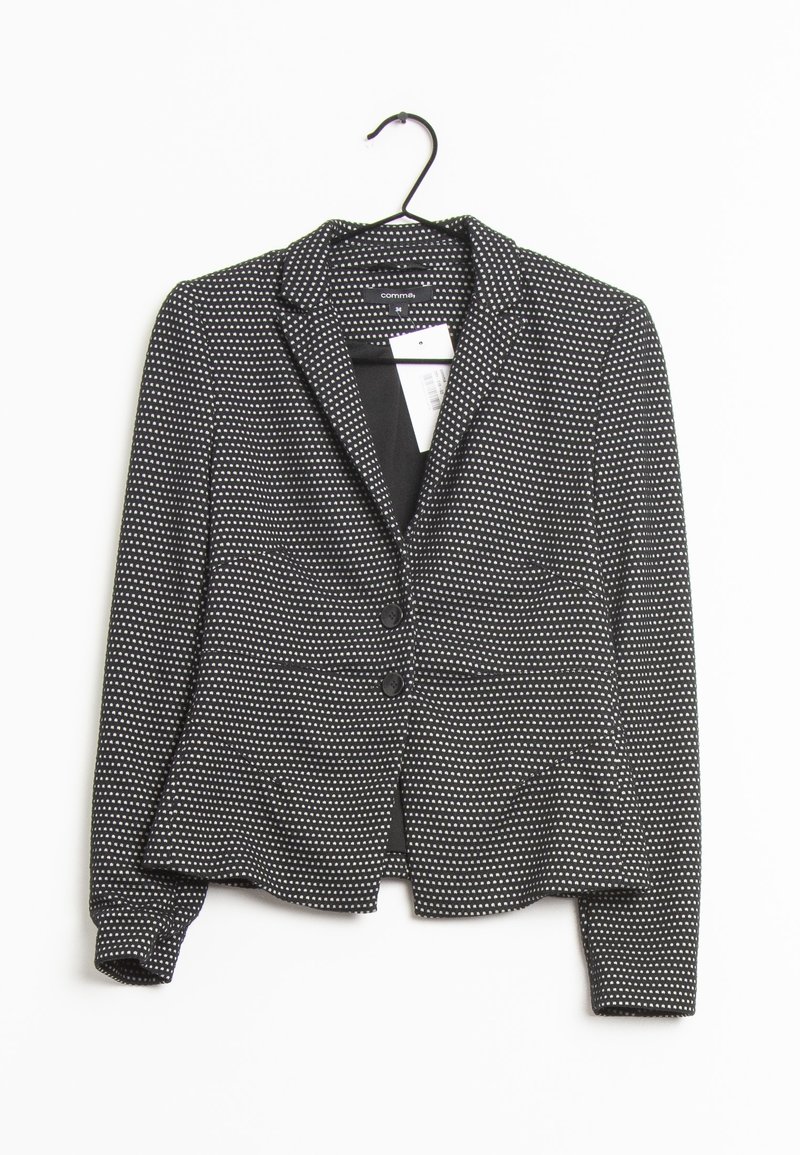 Černý blazer s bílými puntíky, dvěma předními knoflíky a klopami. Vyroben z texturované látky, zavěšen na háčku.