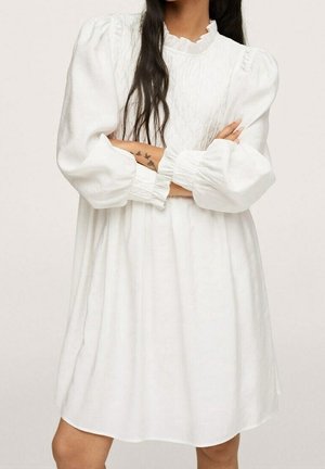 Biała, luźna sukienka z bufkami oraz falbaniastym dekoltem. Teksturowany detal w talii, długość do kolan, wykonana z lekkiego materiału.