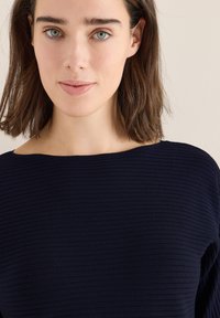 Granatowa bluzka z prążkowanego dzianiny o szerokim dekolcie i krótkich rękawach, z teksturowanym materiałem i gładkim wykończeniem.