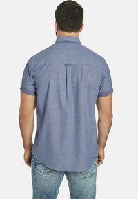 Kurzarm, Button-Down-Hemd aus hellblauem Chambray-Stoff. Verfügt über einen Rückenfalten, abgerundeten Saum und hochgekrempelte Ärmel. Lässiges Design.