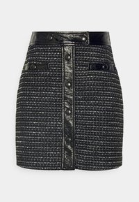 Korte zwarte tweed rok met een glanzende zwarte nep leren tailleband, met een knoopsluiting aan de voorkant en twee zijzakken. Gelaagd stof met een ruitpatroon.