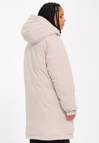 Lys beige lang jakke med hætte, der har elastiske manchetter og en glat, polstret tekstur. Enkel, moderne design uden synlige mønstre.