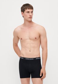 Black boxer shorts with a snug fit, made from stretch fabric, featuring a white "BJÖRN BORG" branded waistband. Designed for comfort and support.
